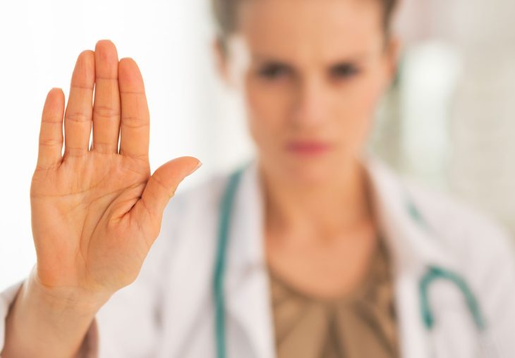 Ärztin hebt Hand zu Stoppzeichen, symbolisiert Medical Gaslighting